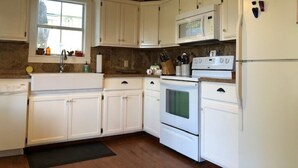 A kitchen with white cabinets, a microwave, an oven, and a refrigerator.