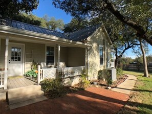 A single-story house with a porch, a covered outdoor seating area, and a small garden.