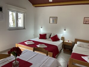 Une chambre d’hôtel avec un lit, une table ornée d’un vase de fleurs et une fenêtre.