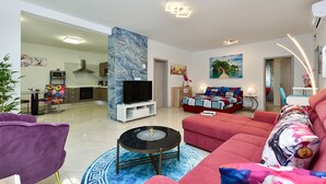 Ein modernes Wohnzimmer mit Fernseher, Sofa und Couchtisch.