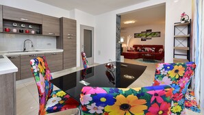 Eine moderne Küche mit Essbereich, ausgestattet mit einem Glastisch und stuhlförmigen Sitzgelegenheiten mit Blumenmuster.
