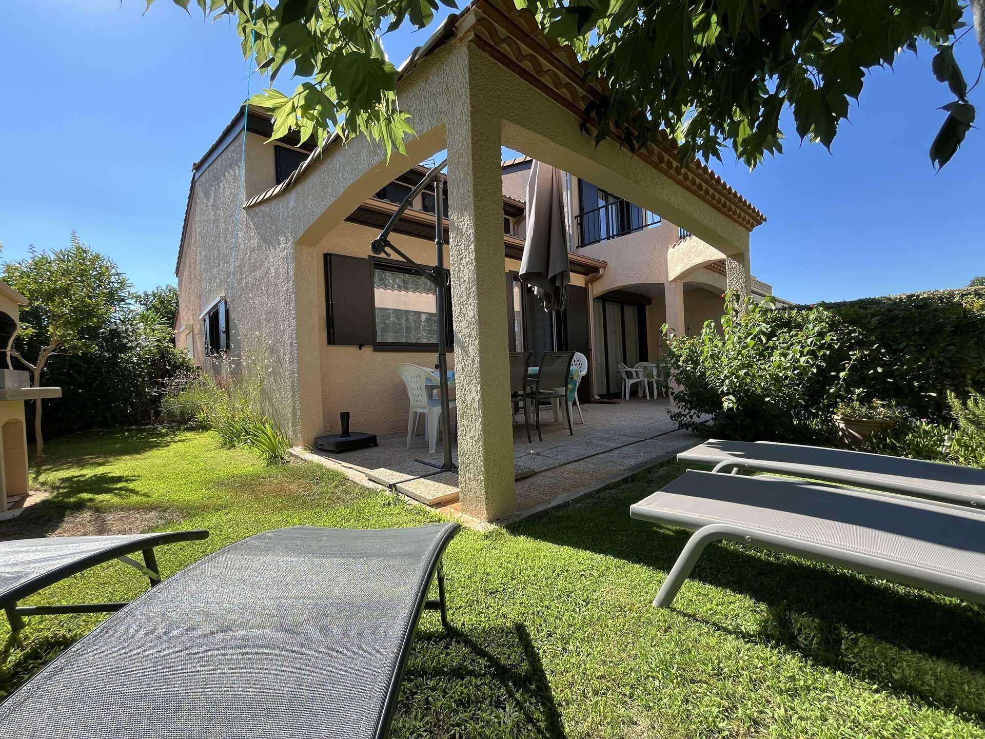 Un bâtiment à deux étages doté d’un patio, d’un espace extérieur aménagé avec des sièges et d’une pergola.