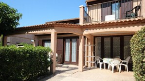 A two-story building with a patio area featuring outdoor seating and a metal drying rack. - Corner house for 5-7 people, Airco, wifi, Residence PORTES DU SOLEIL at 400m from the beach of... (PORTIRAGNES)