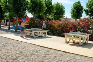 A park with ping pong tables and a playground.