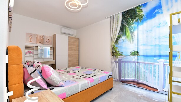 A bedroom with a bed, bedside table, and a view of the ocean.