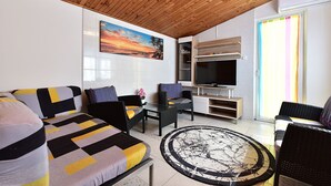 A living room with a sofa, chairs, a TV, and a painting on the wall.