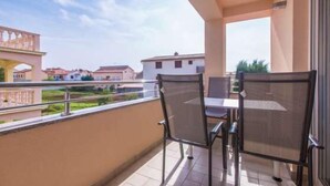 A balcony with a table and chairs, overlooking a residential area with houses and a bridge. - Apartment 927/2176 (Istria - Medulin), 300m from the beach (Medulin)