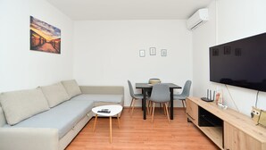A modern living room with a sofa, a dining table with chairs, a flat-screen TV, and a small table with a bowl. - Apartment 928/2196 (Istria - Stinjan), 800m from the beach (Stinjan)