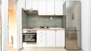 A compact kitchen with white cabinets, a stainless steel refrigerator, and a built-in oven. - Apartment 928/2196 (Istria - Stinjan), 800m from the beach (Stinjan)
