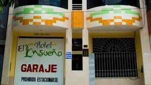 Un edificio de varios pisos con entrada a un garaje, un cartel que indica 'El Hotel Insurgente' y 'GARAGE', y un letrero que dice 'PROHIBIDO ESTACIONARSE'.