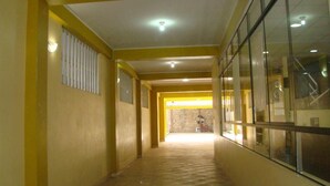 Un pasillo con paredes amarillas y piso de madera que conduce a una habitación luminosa con ventana y escalera.