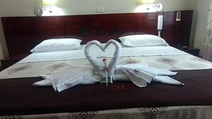 Habitación de hotel con cama, una toalla dispuesta en forma de corazón y cabecera de madera con el nombre 'CASUERO' a la vista.