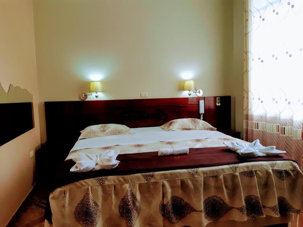 A neatly made bed with a patterned bedspread, two bedside lamps, and a headboard.