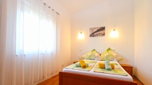 A bedroom with a wooden bed, white curtains, and two wall-mounted lights.