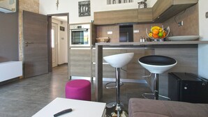 A modern kitchen with a built-in oven, a fruit bowl, and a bar area with stools. - Apartment 934/23284 (Istria - Fažana), 500m from the beach (Fažana)