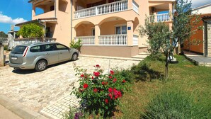 A two-story building with a balcony, a car parked in front, and a garden with flowers. - Apartment 934/23284 (Istria - Fažana), 500m from the beach (Fažana)