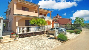 A two-story house with a balcony, a car parked in the driveway, and a clear blue sky. - Apartment 934/23284 (Istria - Fažana), 500m from the beach (Fažana)