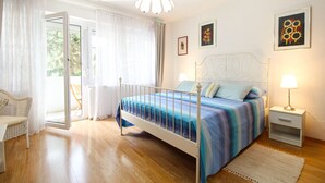 A bedroom with a bed, bedside tables, a chair, and a view of the outdoors.