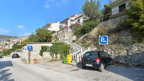 A parking area with a car, a blue parking sign, and a staircase leading to a building with balconies. - Apartment 938/2349 (Istria - Rabac), 300m from the beach (Rabac)