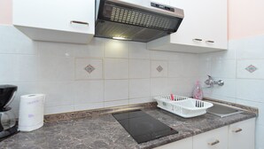 A kitchen with white cabinets, a black induction cooktop, a stainless steel range hood, a marble countertop, a sink with a faucet, and a bottle of hand soap. - Apartment 938/2349 (Istria - Rabac), 300m from the beach (Rabac)