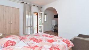 A bedroom with a bed, a wardrobe, a dining area with chairs, and a television. - Apartment 938/2349 (Istria - Rabac), 300m from the beach (Rabac)