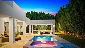 Un espace piscine extérieur moderne, doté d’un jacuzzi, de coins salon et d’un espace repas.