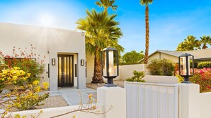 Une maison moderne avec une façade blanche, une porte noire et une entrée fermée par un portail.