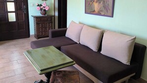 Una sala de estar con sofá, una mesita, un armario y una puerta.