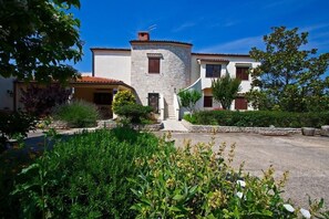 A two-story building with a stone tower, surrounded by lush greenery and a paved driveway. - Apartment 945/2379 (Istria - Medulin), 300m from the beach (Medulin)