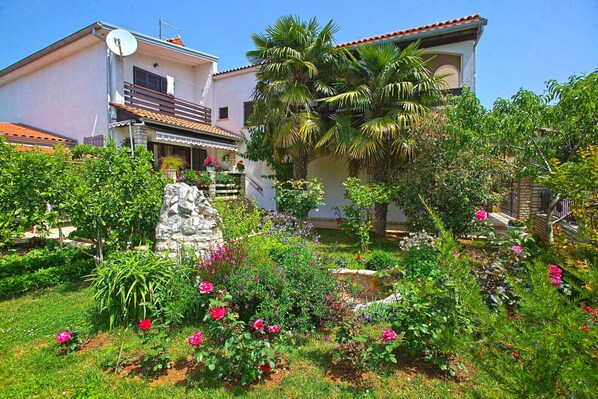 Surrounded by a lush garden, this two-story property features a balcony and a charming stone structure.