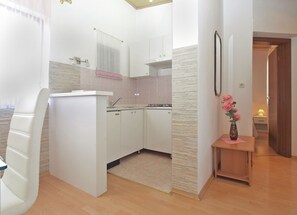 Compact kitchen with sink, stove, and tiled backsplash.