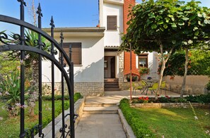 Welcome to a serene garden oasis with a beautifully maintained outdoor space and a charming entrance.