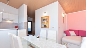 A modern living space with a dining area, a kitchen, and a seating area with a pink sofa.