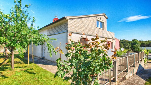 A two-story house with a brick facade, a small balcony, and a garden area with trees and a flower bush. - Apartment 964/2472 (Istria - Premantura), 450m from the beach (Premantura)