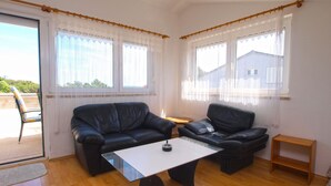 A living room with a black leather sofa, a white coffee table, and two windows with sheer curtains. - Apartment 964/2472 (Istria - Premantura), 450m from the beach (Premantura)