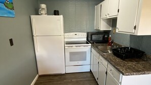 A compact kitchen with white appliances, a microwave, and a coffee maker on the countertop. - 2 bedrooms with shared pool. apt1 (Hampton)