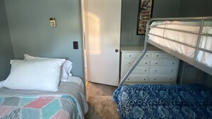 A bedroom with two beds, a dresser, and a door leading to another room. - 2 bedrooms with shared pool. apt1 (Hampton)