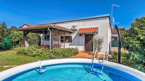 Una casa con piscina, patio coperto e antenna parabolica.