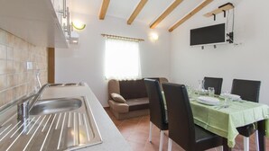 Una cucina moderna con lavandino, un'area pranzo con tavolo apparecchiato per due e una televisione a parete.