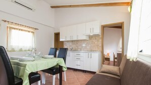 Zona pranzo con tavolo apparecchiato per quattro persone, divano e cucina sullo sfondo.