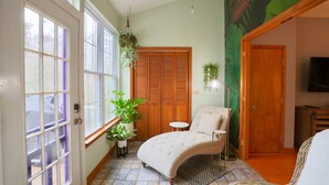 A room with a large window, a chair, a small table, and a door.
