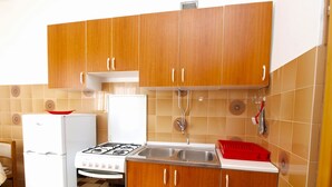 Una cocina compacta con armarios de madera, un refrigerador blanco, una estufa y un lavamanos.
