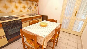 A compact kitchen with a gas stove, oven, and a dining table with chairs. - Apartment 981/2644 (Istria - Rabac), 500m from the beach (Rabac)