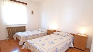 A bedroom with two single beds, wooden flooring, a radiator, and bedside lamps. - Apartment 981/2644 (Istria - Rabac), 500m from the beach (Rabac)