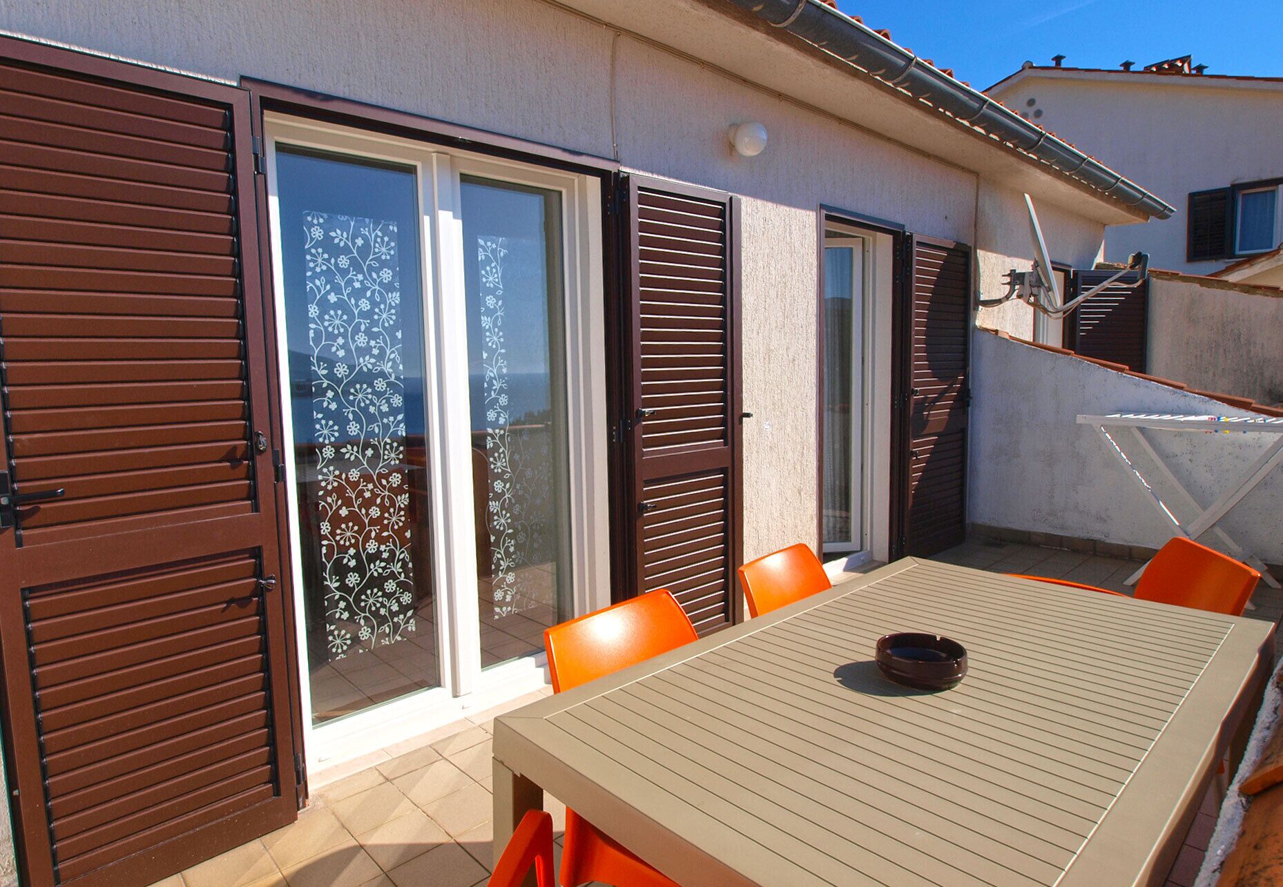 A patio with a table and chairs, a sliding glass door, and a staircase.