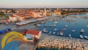 Un puerto deportivo con barcos amarrados, un pueblo al fondo y un edificio con techo rojo en primer plano.