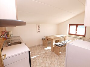 Uma cozinha compacta com pia, uma mesa de madeira e um banco.