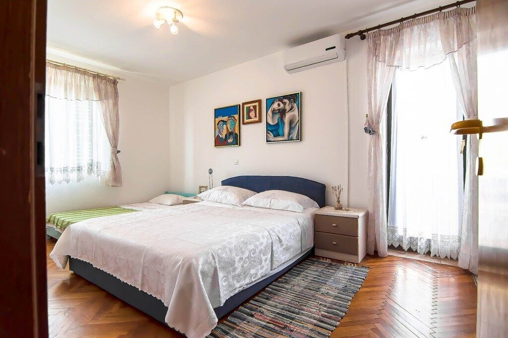 A bedroom with a bed, nightstands, a dresser, and artwork on the wall.
