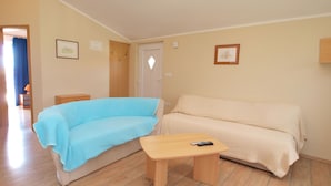 A room with a blue sofa, a beige sofa, and a wooden table with a remote control.