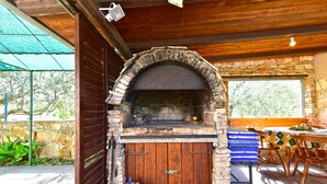 An outdoor brick oven with a stone arch, wooden door, and a metal bucket with tools. - House 1012/3351 (Istria - Fažana), 1000m from the beach (Fažana)